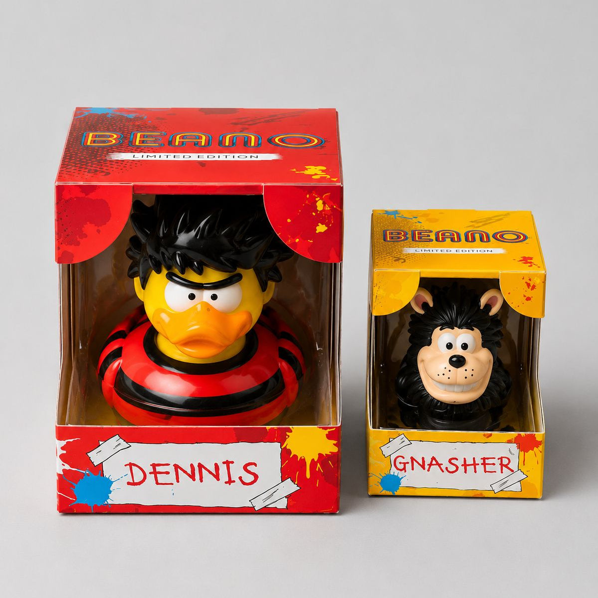 Two limited edition 'Beano' figures, Dennis and Gnasher, in their packaging on a gray background.